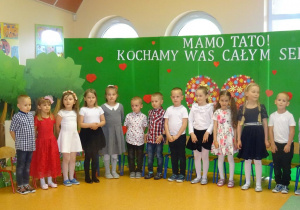 Dzieci stoją na tle dekoracji na Dzień Rodziny, śpiewają piosenkę.